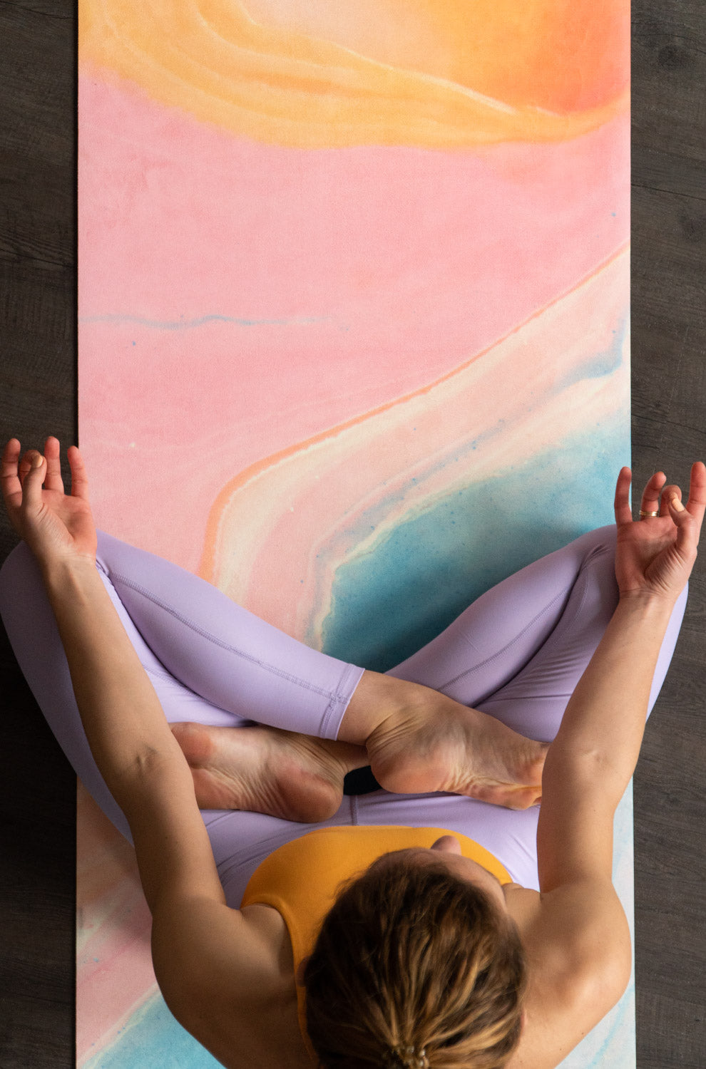 Frau macht Yoga auf 2-in-1-Yogamatte und Handtuch von MALA Yoga im Design Mango Smoothie in leuchtenden Farben. Design im Acrylpouring Verfahren hergestellt.