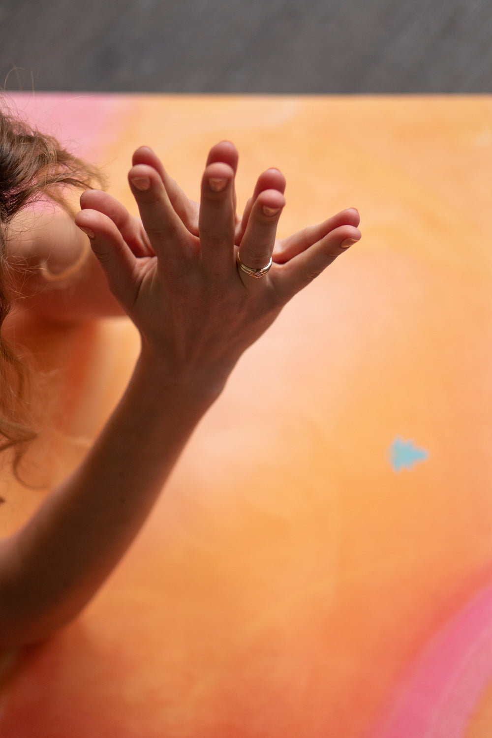 Hände auf 2-in-1-Yogamatte und Handtuch von MALA Yoga im Design Mango Smoothie in leuchtenden Farben. Design im Acrylpouring Verfahren hergestellt.