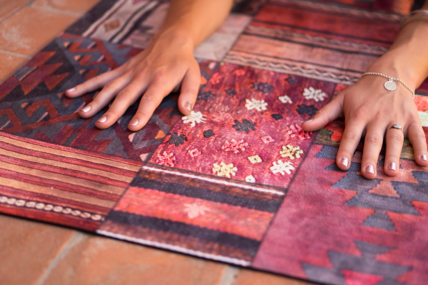 Hände auf 2-in-1-Yogamatte und Handtuch von MALA Yoga im Design Marrakesh. Teppich Muster.
