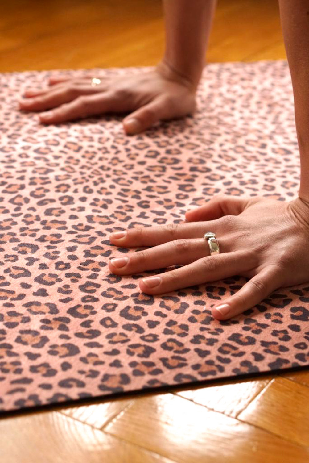 Frau macht Yoga auf 2-in-1-Yogamatte und Handtuch von MALA Yoga im Design Honey Leopard in warmen Farben.